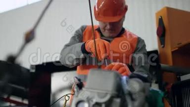 一名工人，戴着头盔，穿着工作服，修理汽车发动机的轻微故障